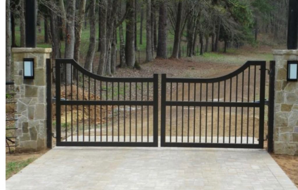 Custom simple Atlanta driveway gate installed between two stacked stone pillars