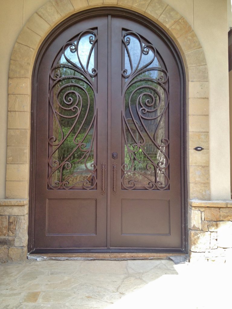 Ornate custom iron door in Atlanta with swooping lines and brown copper patina